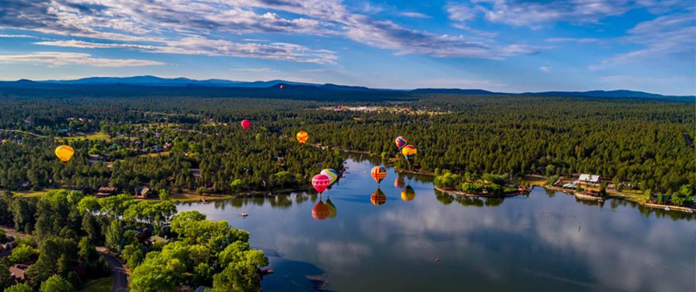 A group of balloons floating in the air over water.